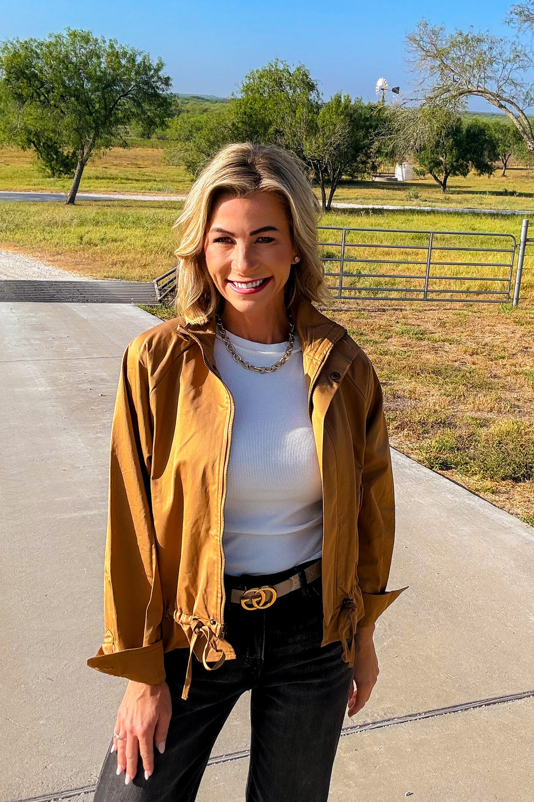 Woman wearing the Prescott camel lightweight utility jacket over a white tank top with black jeans