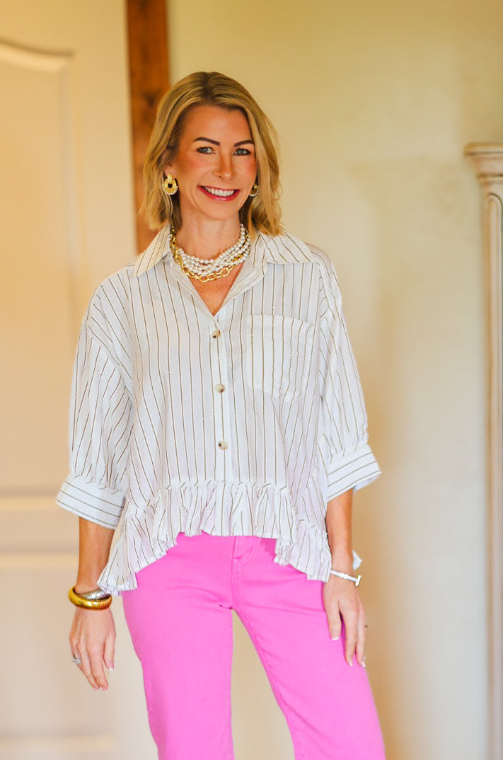 Woman in a white striped shirt and pink pants standing in a room with a dresser.